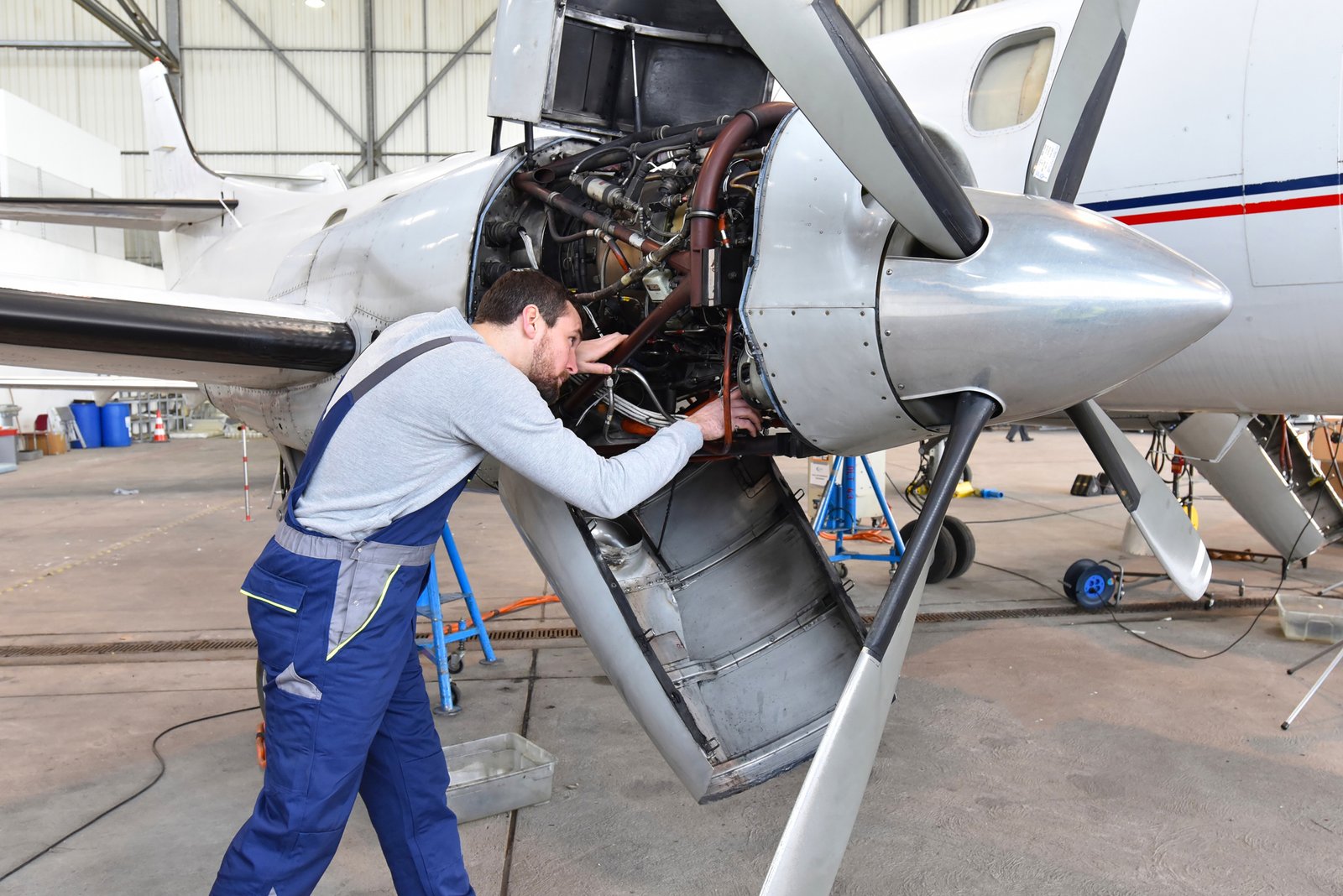 Aircraft mechanic repairs an aircraft engine in an airport hangar